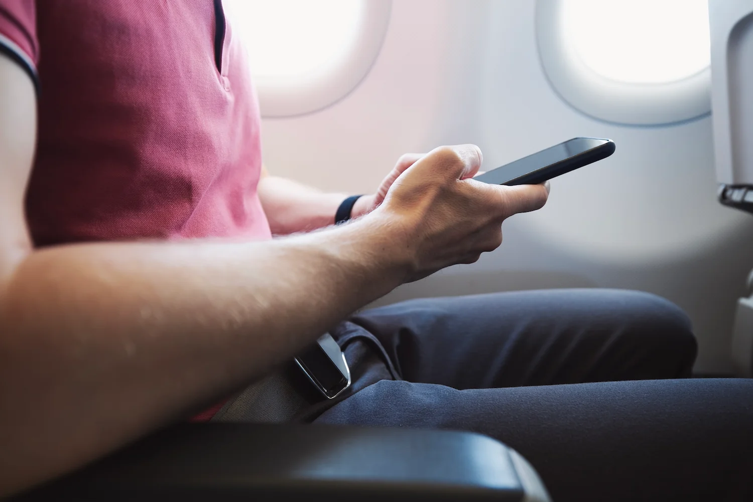 Homem com smartphone em avião, representando o sucesso do WhatsApp para vendas no case TAM Aviação Executiva.